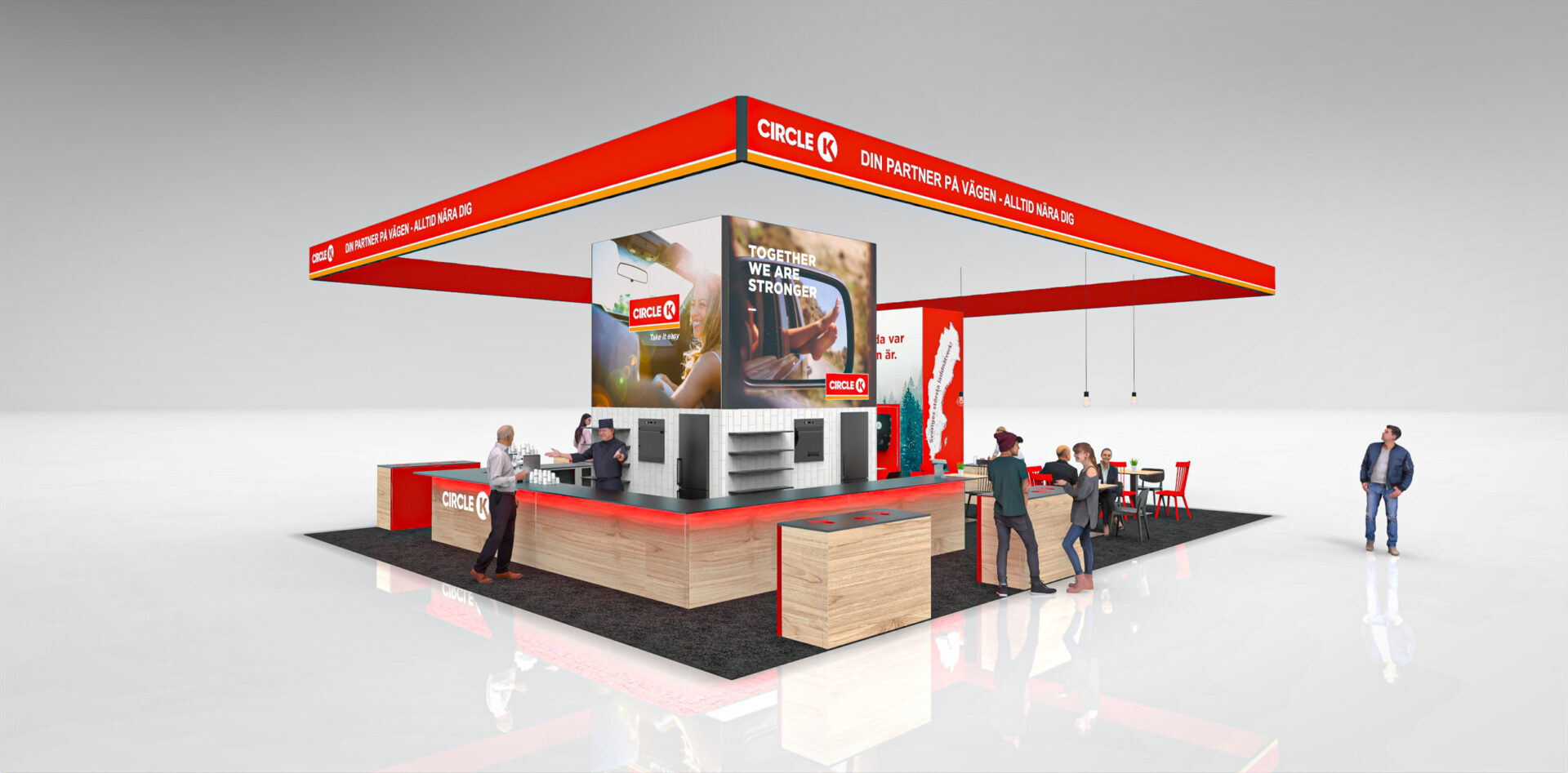 A modern trade show booth for Circle K features a red and white color scheme, wooden counters, seating areas, digital displays, and several people interacting in a bright, open space.