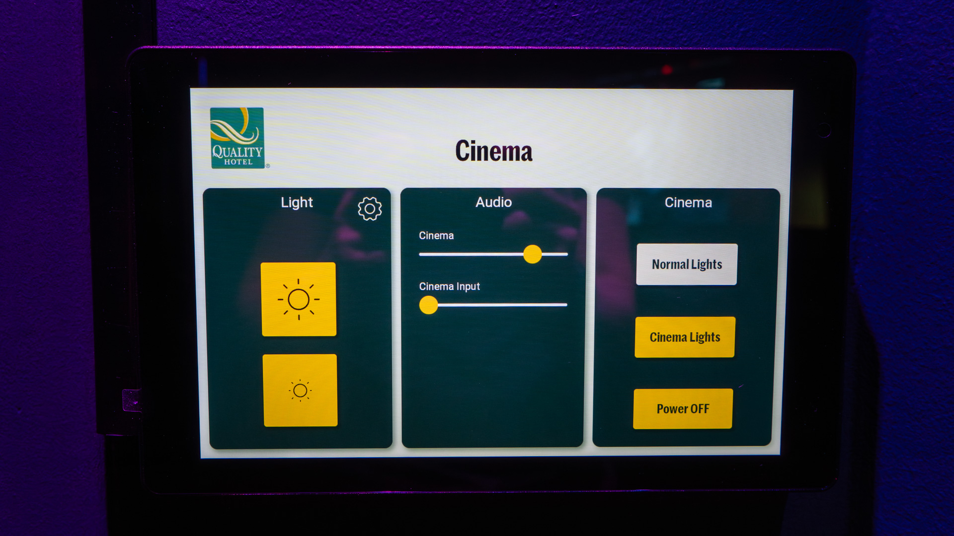 A digital control panel screen displays settings for light, audio, and cinema at a Quality Hotel. Options include adjusting lighting, audio levels, and buttons for normal lights, cinema lights, and power off.